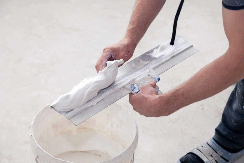 rabotnik-derza-spatel-s-rastvorom-zamazki-stroitel-kladet-stukaturku-v-spatel-v-vedro (1).jpg